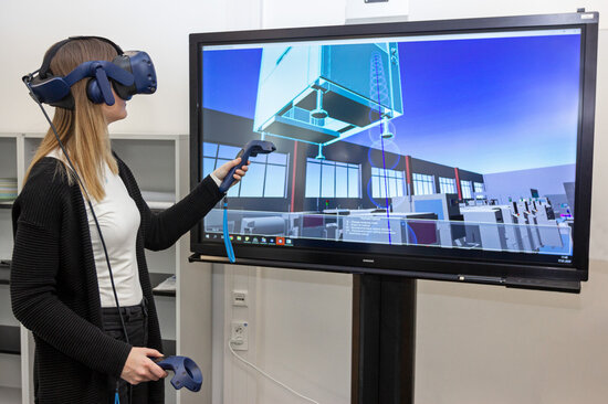 Mitarbeiterin nutzt VR-Brille für digitale Zwillinge und virtuelle Fertigungsplanung.