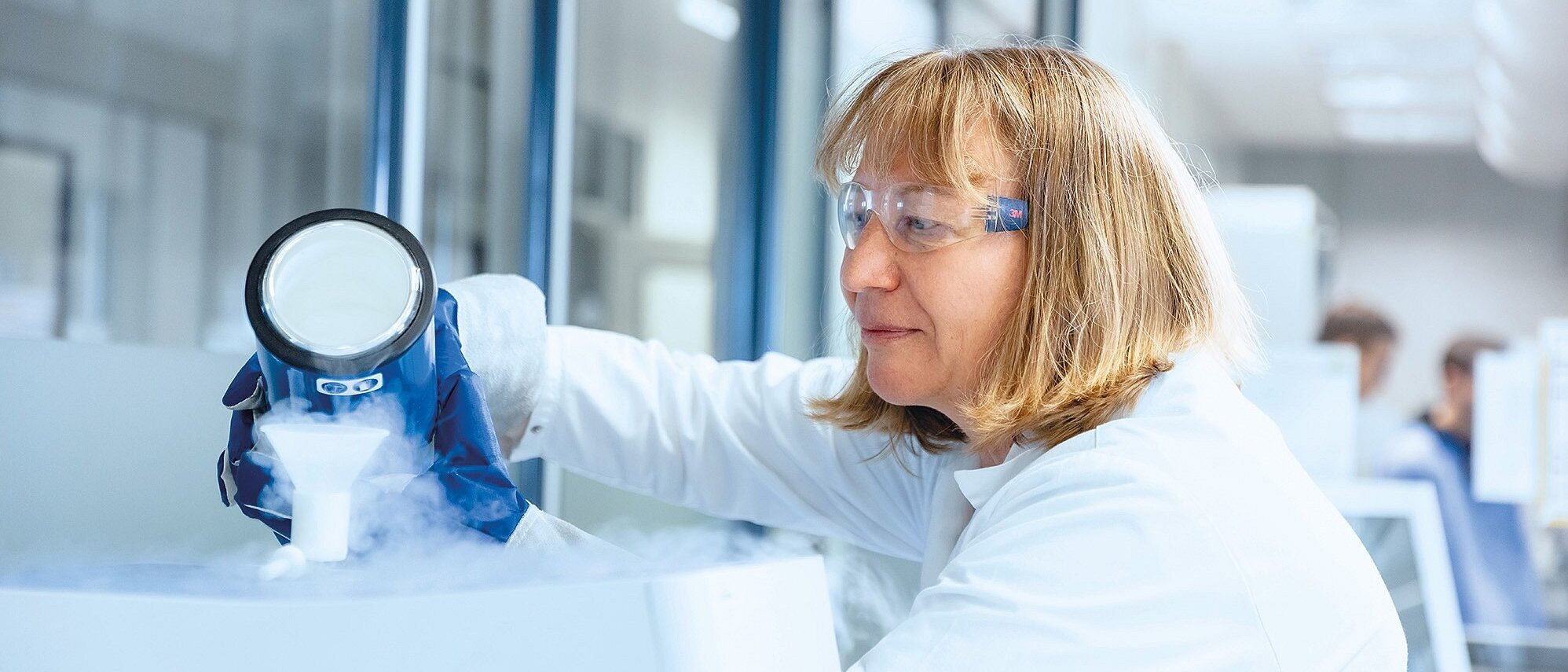 Mitarbeiterin aus dem Labor mit einem dampfenden Stoff