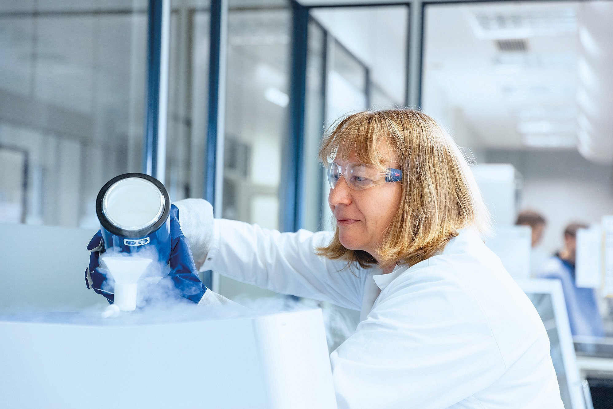 Mitarbeiterin aus dem Labor mit einem dampfenden Stoff