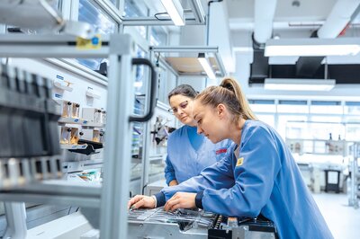 Mitarbeiter der Zollner Elektronik AG arbeiten in Fertigung, Hinweis auf vielfältige Jobangebote.