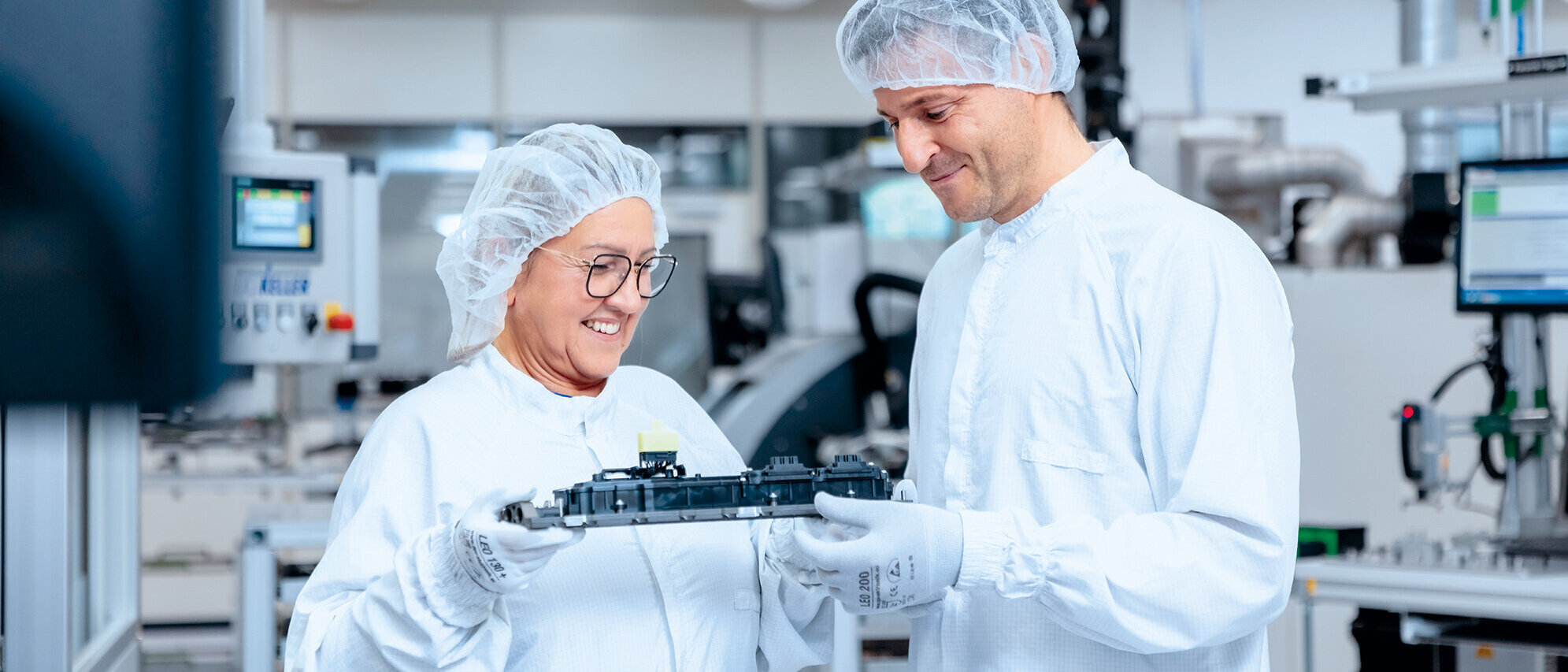 Zwei Mitarbeiter in der Produktion schauen glücklich auf ein Produkt, welches sie gemeinsam halten 
