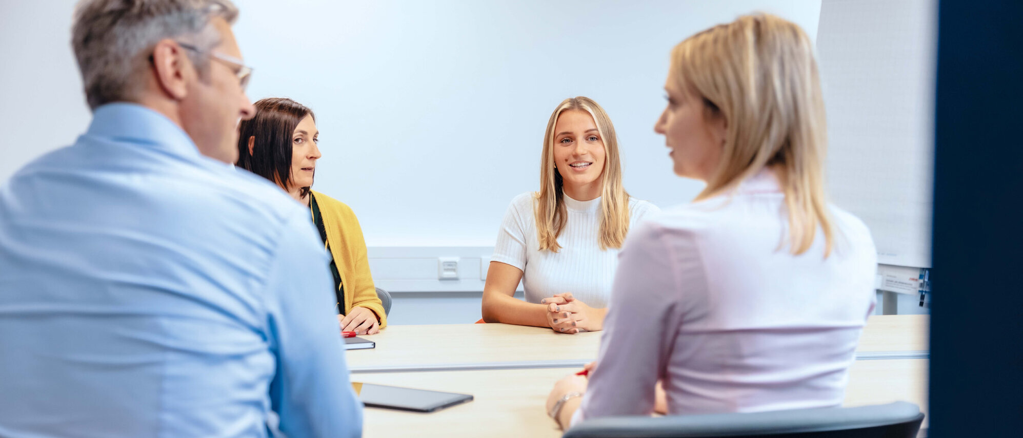 4 Personen sitzen an einem Tisch und unterhalten sich in der Gruppe