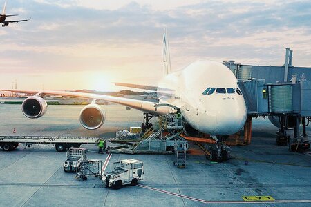 Großraumflugzeug am Flughafen mit angeschlossener Fluggastbrücke und Bodenfahrzeugen