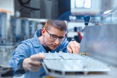 Mitarbeiter arbeitet an Bauteilen in der Mechanikproduktion mit CNC- und Lasertechnologien.
