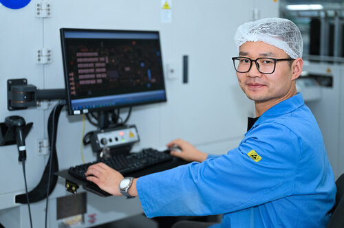 Mitarbeiter aus China bedient eine Maschine mit seinem Computer 