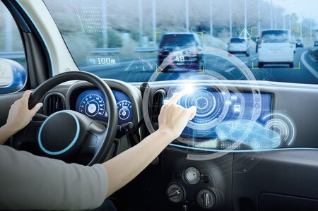 Innenansicht eines Autos mit digitalem Head-up-Display und futuristischen Fahrinformationen.