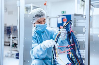 Mitarbeiter der Zollner Elektronik AG arbeitet im Reinraum an Kabelmontage, Hinweis auf Flexibilität und Karrierechancen.