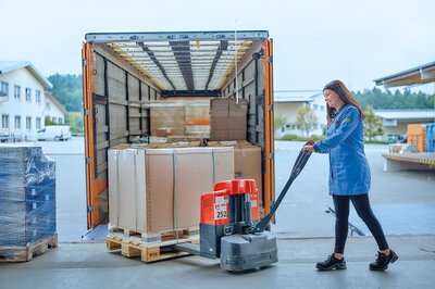 Paletten mit Ersatzteilen werden per Hubwagen in einen LKW verladen für effiziente Logistik und schnelle Lieferung.
