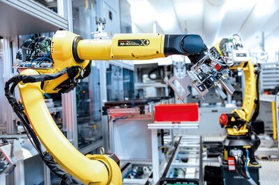 Gelbe Roboterarme in einer Fertigungs- oder Produktionshalle 