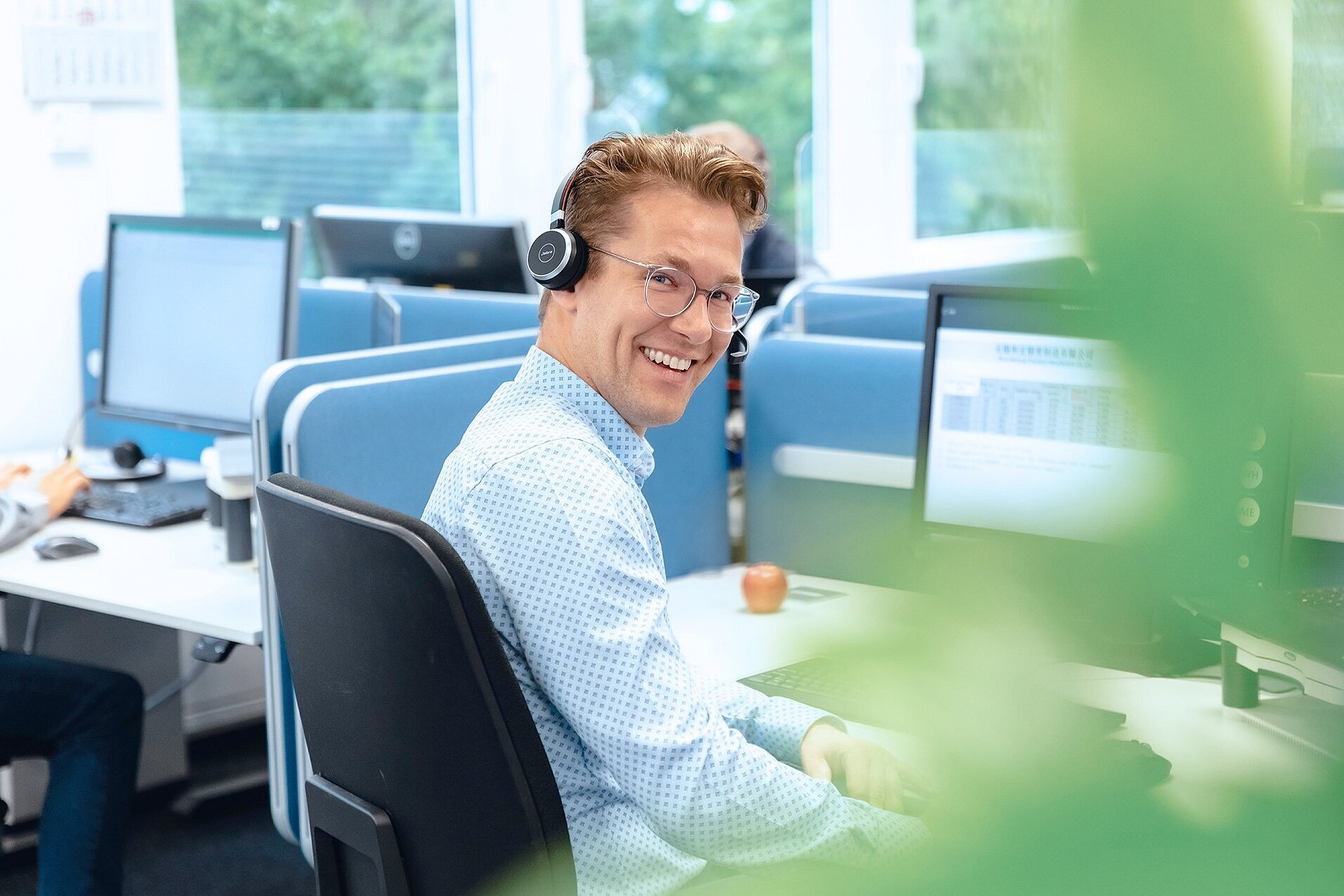 Mitarbeiter im Büro mit Headset unterstützt Kunden im After-Sales-Service für umfassende Betreuung.