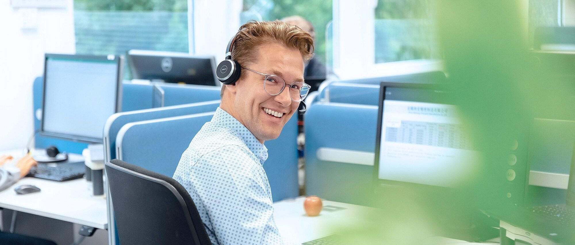 Mitarbeiter im Büro mit Headset unterstützt Kunden im After-Sales-Service für umfassende Betreuung.
