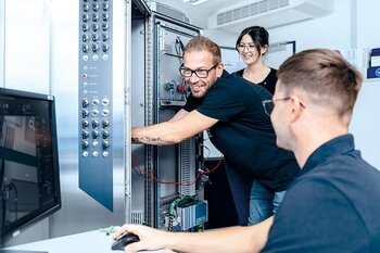 Mitarbeiter arbeiten am Schaltschrankdesign und prüfen Komponenten am Schaltschrank.