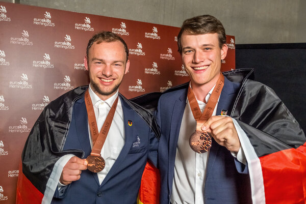 Zwei Mitarbeiter der Zollner Elektronik AG mit deutscher Flagge und Bronzemedaillen bei EuroSkills 2025