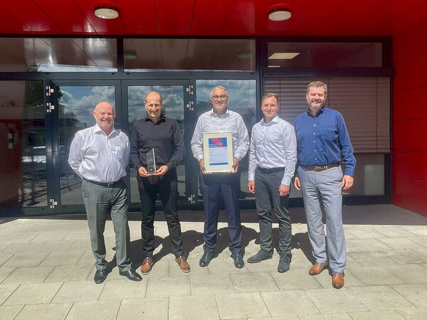 Gruppe vor Gebäude mit QIAGEN Supplier Award 2024 Auszeichnung