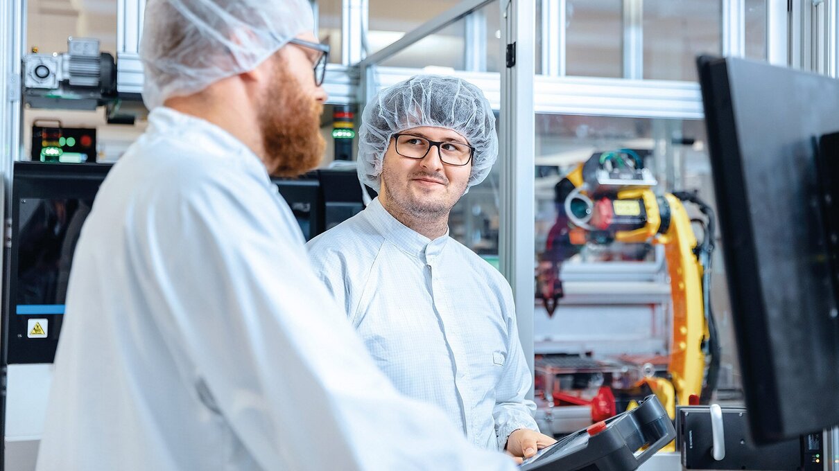Zwei Mitarbeiter steuern einen Roboter 
