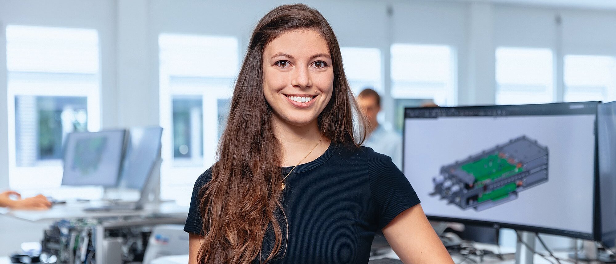 Mitarbeiterin steht vor einem Bildschirm mit CAD-Modell im Bereich Research & Development.
