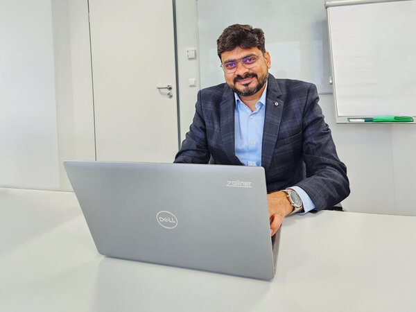 Mitarbeiter aus Indien sitzt im Bürogebäude und arbeitet am Laptop 