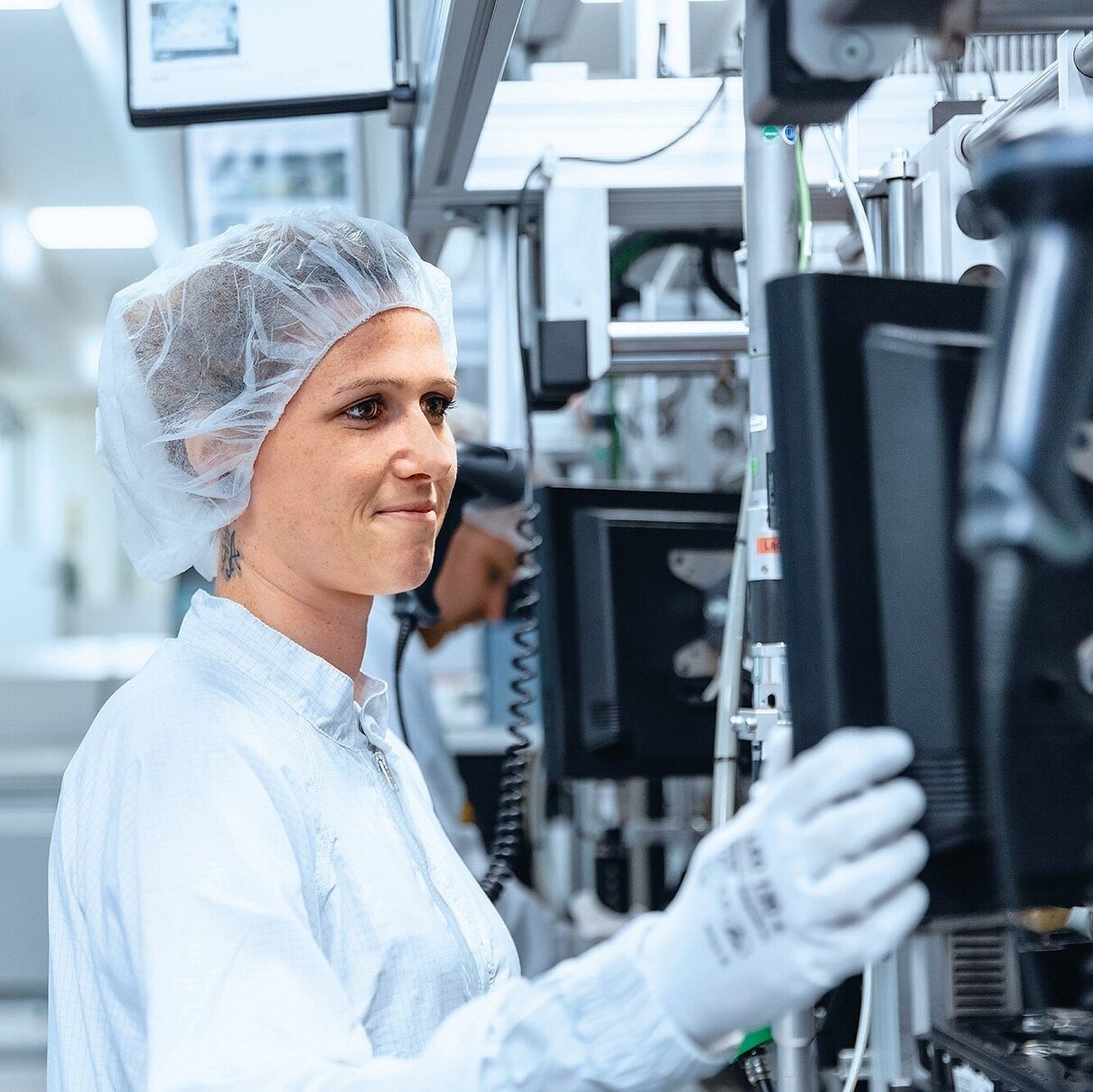 Mitarbeitende in Reinraumumgebung bedient Produktionsanlagen für mechatronische Systeme.