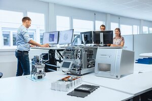 Mitarbeitende arbeiten an mechatronischen Systemen mit Hardware und Software am Arbeitsplatz.