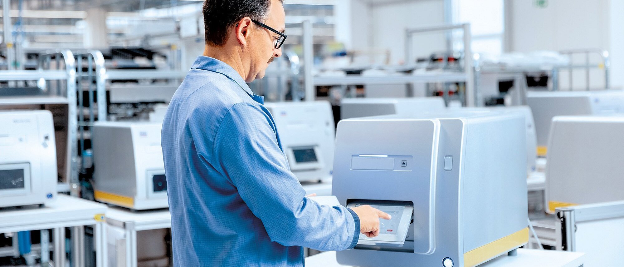 Mitarbeiter in ESD-Schutzkleidung bedient ein Prüfgerät in einer modernen Elektronikfertigung der Zollner Elektronik AG zur Qualitätssicherung