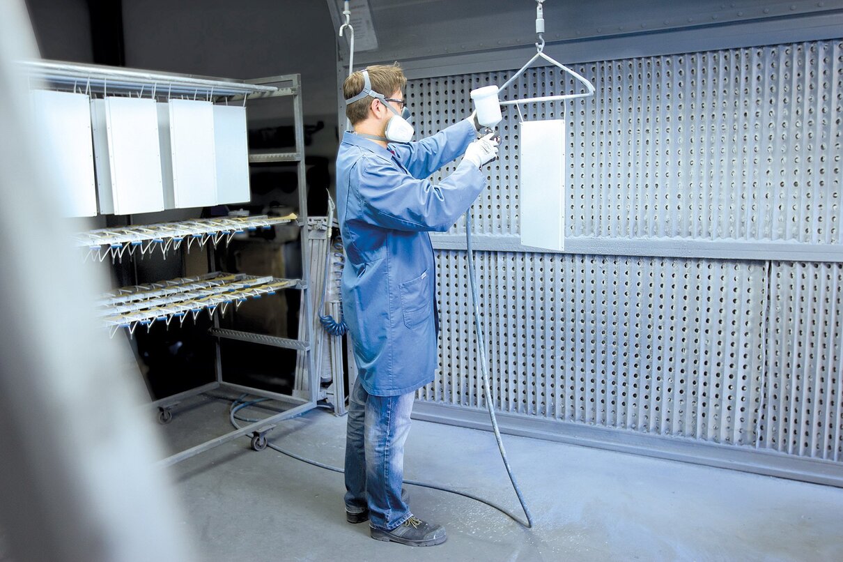 Mitarbeiter in der Produktion führen eine Nasslackierung durch.