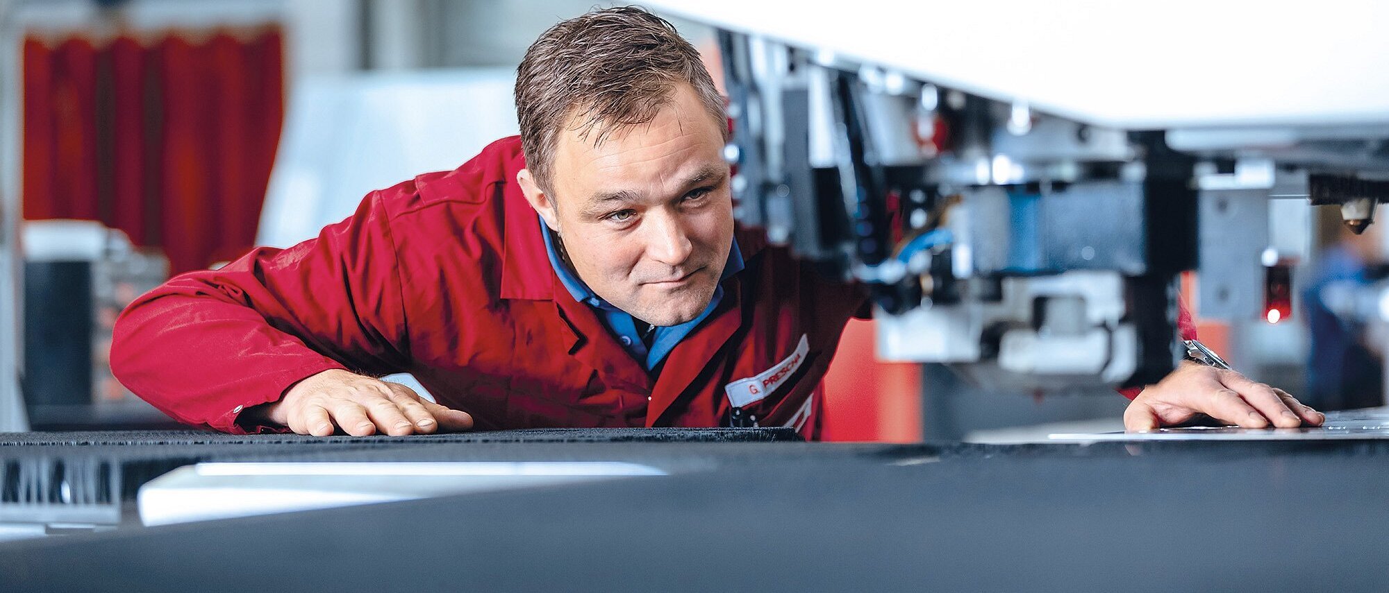 Mitarbeiter der Zollner Elektronik AG arbeitet an einer mechanischen Fertigungsmaschine für Blech-, Dreh- und Frästeile in der Produktion.