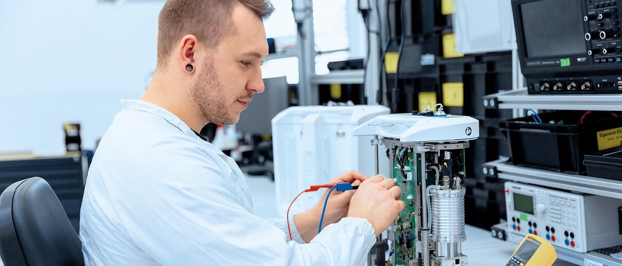 Mitarbeiter der Zollner Elektronik AG prüft elektronische Baugruppe mit Messgeräten im Labor