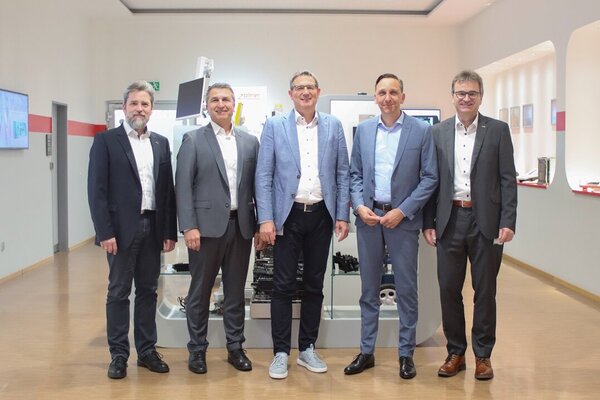 Gruppenfoto mit 5 Personen, die zufrieden in die Kamera schauen 