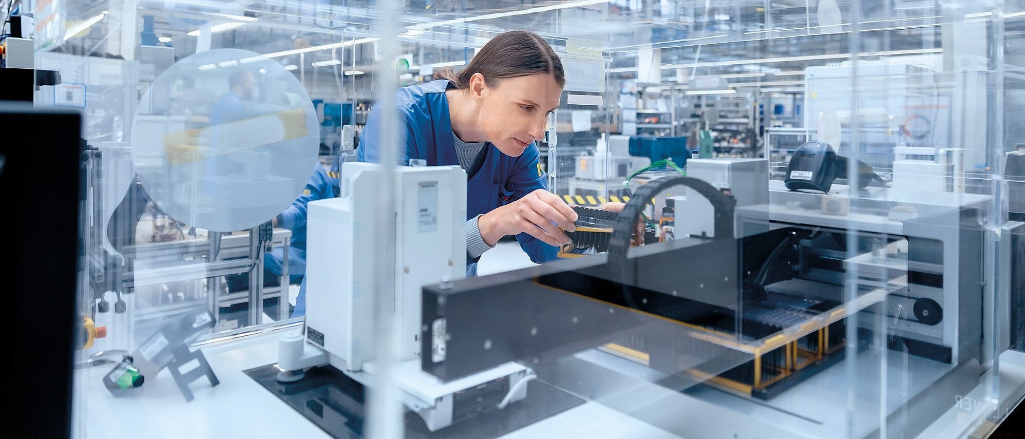 Mitarbeiterin arbeitet in einer modernen Produktionshalle an einer Maschine