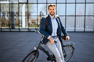 Mitarbeiter der Zollner Elektronik AG sitzt auf einem Fahrrad vor einem modernen Bürogebäude im Rahmen des Fahrradleasing-Angebots.